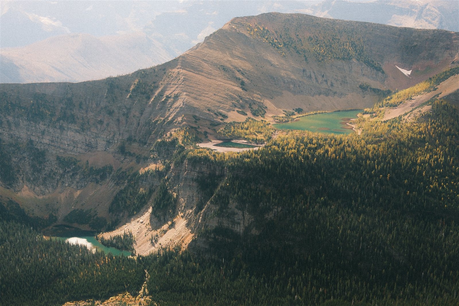 Two alpine lakes at different elevations among forested slopes and rocky ridges