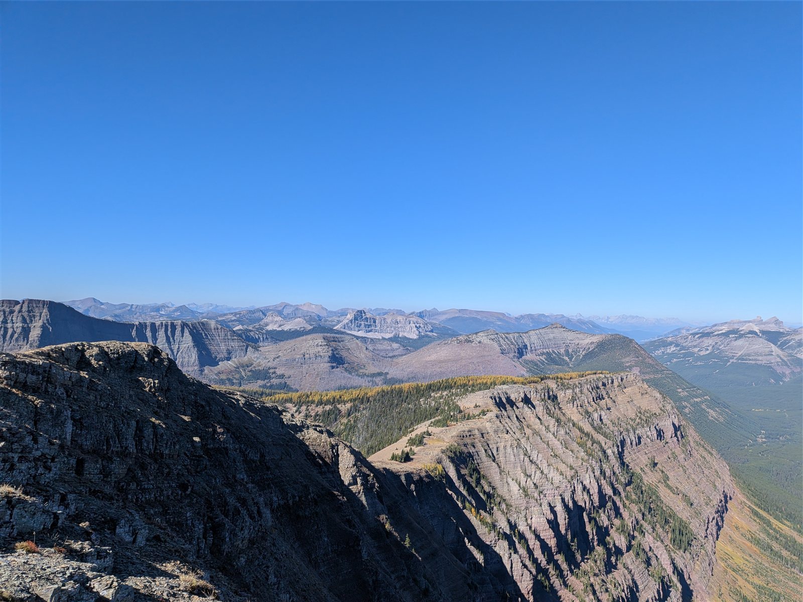 Layered mountain ridges and exposed cliffs stretching into the distance under a blue sky