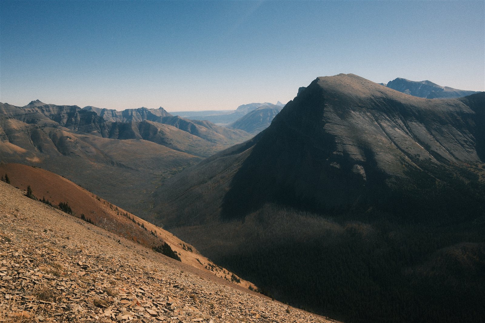 A broad view from Avion Ridge across a deep valley toward a sharply angled mountain