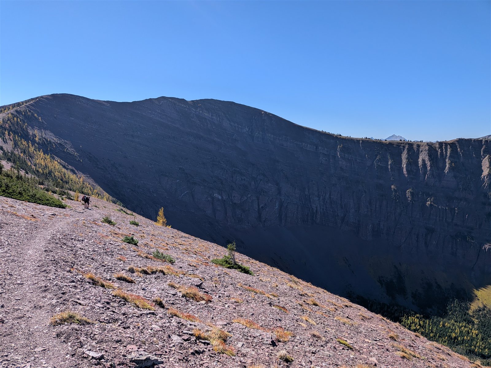 A backward view across a rocky slope toward the long, shadowed face of Avion Ridge